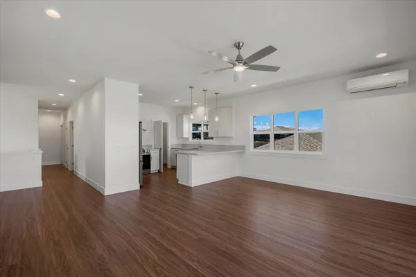 an empty room with wooden floor and a kitchen