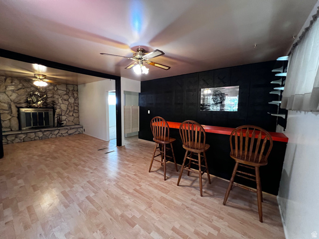 338 South 300 West Helper, UT 84526 - Photo 8 of 20 Dining space featuring a ceiling fan, light wood-type flooring, a stone fireplace, and a dry bar