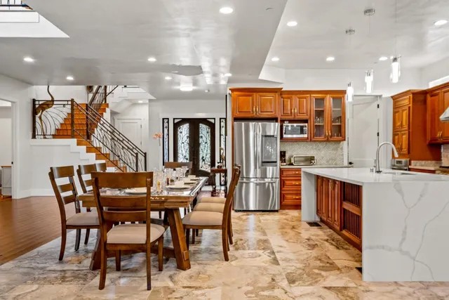 a dining room with stainless steel appliances kitchen island granite countertop a dining table and chairs