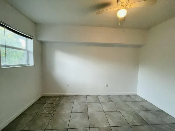 an empty room with a ceiling fan and a rug
