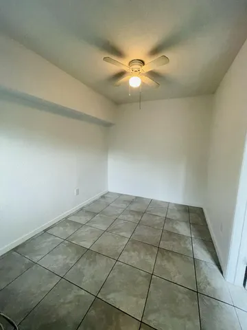 an empty room with a ceiling fan and window