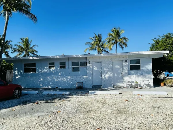 a view of a house with a yard and palm trees