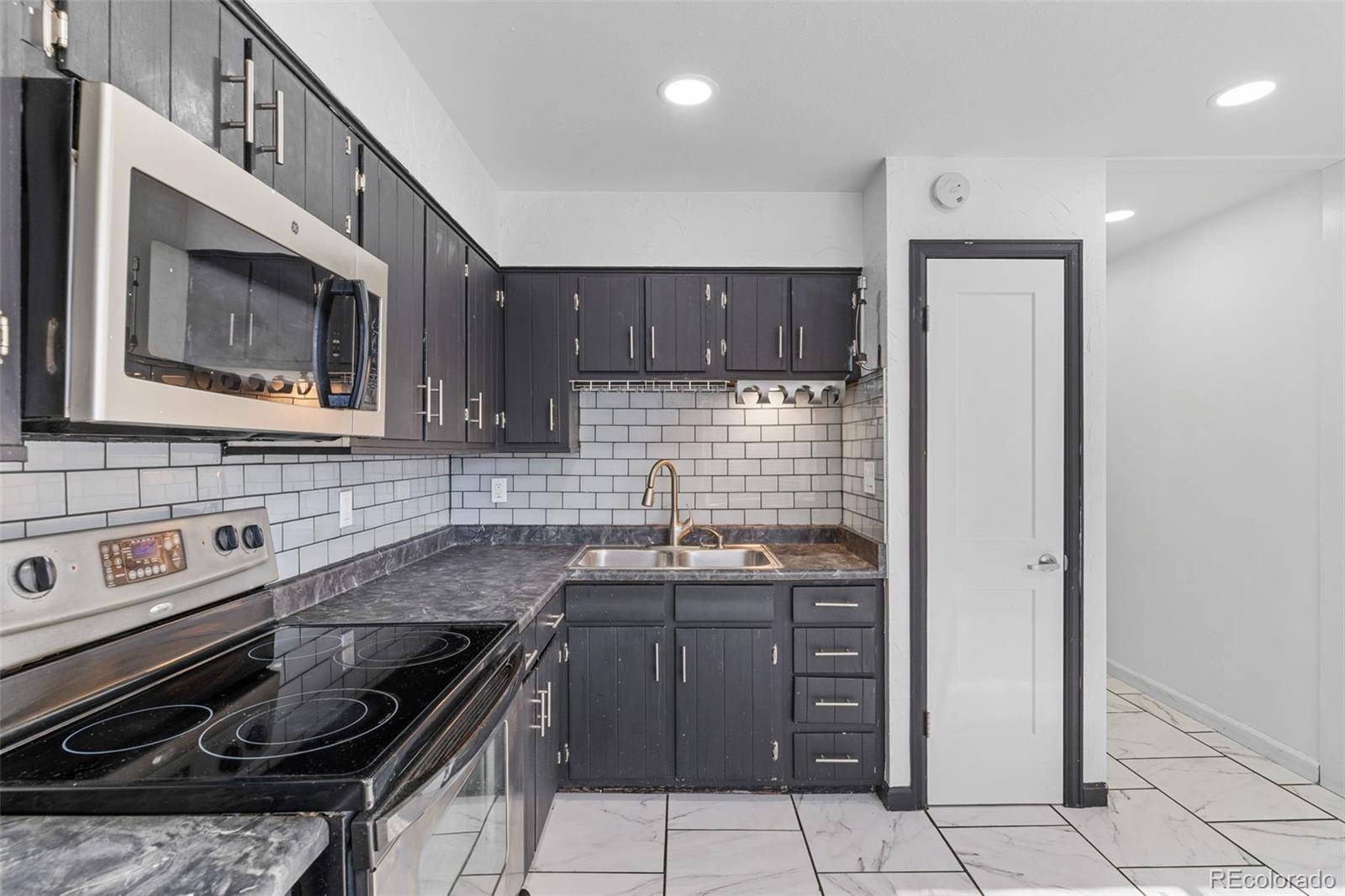 1630 Chester Street Aurora, CO 80010 - Photo 14 of 31 a kitchen with granite countertop a stove sink and cabinets