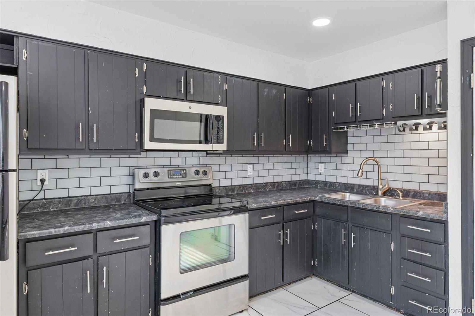 1630 Chester Street Aurora, CO 80010 - Photo 15 of 31 a kitchen with stainless steel appliances granite countertop a sink stove and microwave
