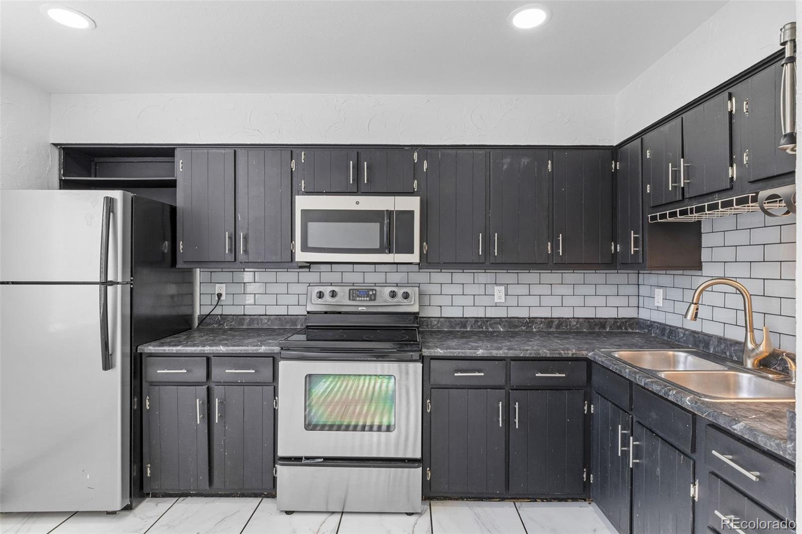 1630 Chester Street Aurora, CO 80010 - Photo 16 of 31 a kitchen with stainless steel appliances granite countertop a sink stove and refrigerator