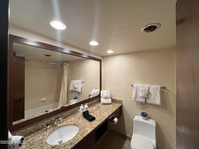 a bathroom with a granite countertop sink mirror and toilet