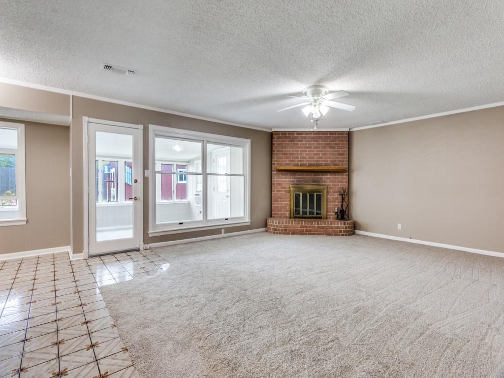 1216 Manning Street Benbrook, TX 76126 - Photo 4 of 26 Unfurnished living room featuring ornamental molding, a textured ceiling, a fireplace, tile patterned flooring, and ceiling fan