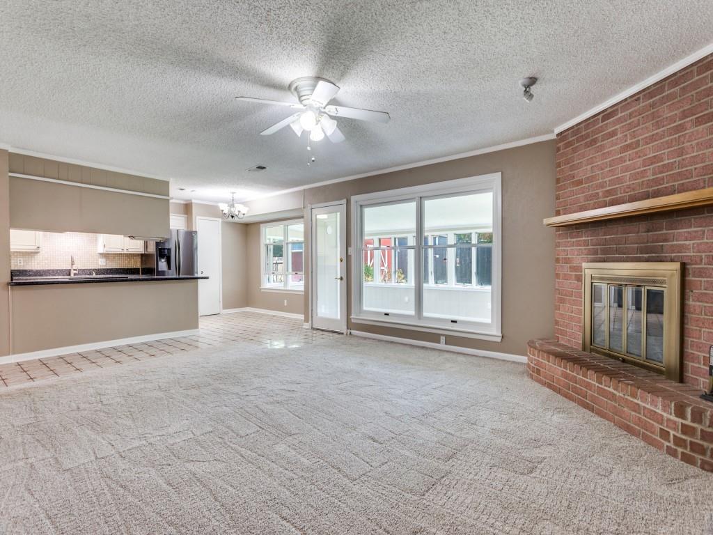 1216 Manning Street Benbrook, TX 76126 - Photo 5 of 26 Unfurnished living room featuring light carpet, ornamental molding, a brick fireplace, ceiling fan, and a chandelier