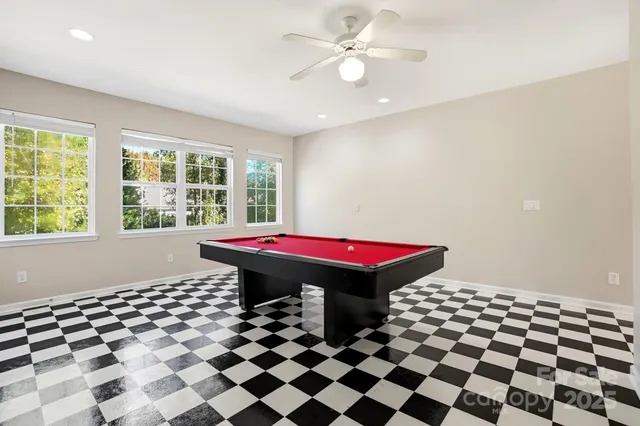 a room with a black white checkered floor with a gaming machine and dining chairs