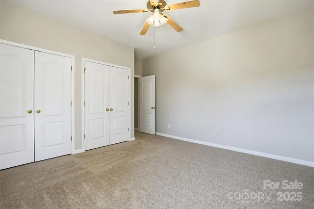a view of an empty room and chandelier fan