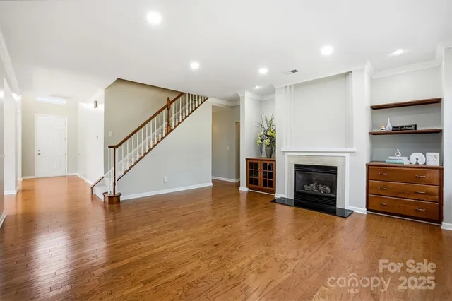a view of an empty room with wooden floor a fireplace and a window