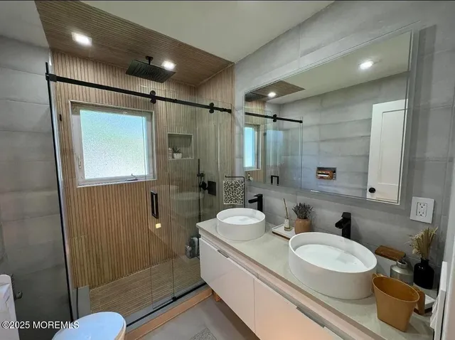a bathroom with a double vanity sink toilet mirror and shower