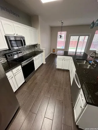 a kitchen with granite countertop a stove a sink and a refrigerator