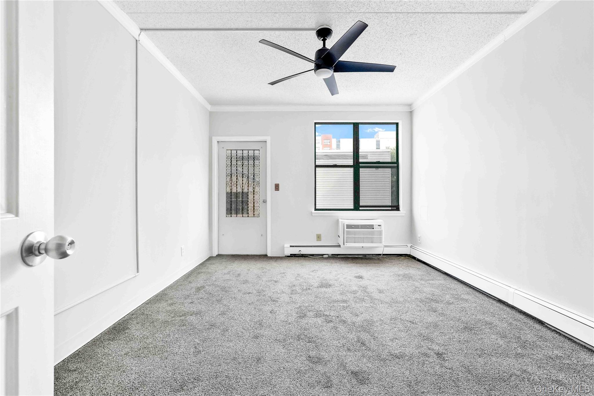 758 Brook Avenue, Unit 56C Bronx, NY 10455 - Photo 3 of 16 Unfurnished bedroom featuring ornamental molding, carpet floors, ceiling fan, a textured ceiling, and a wall mounted AC