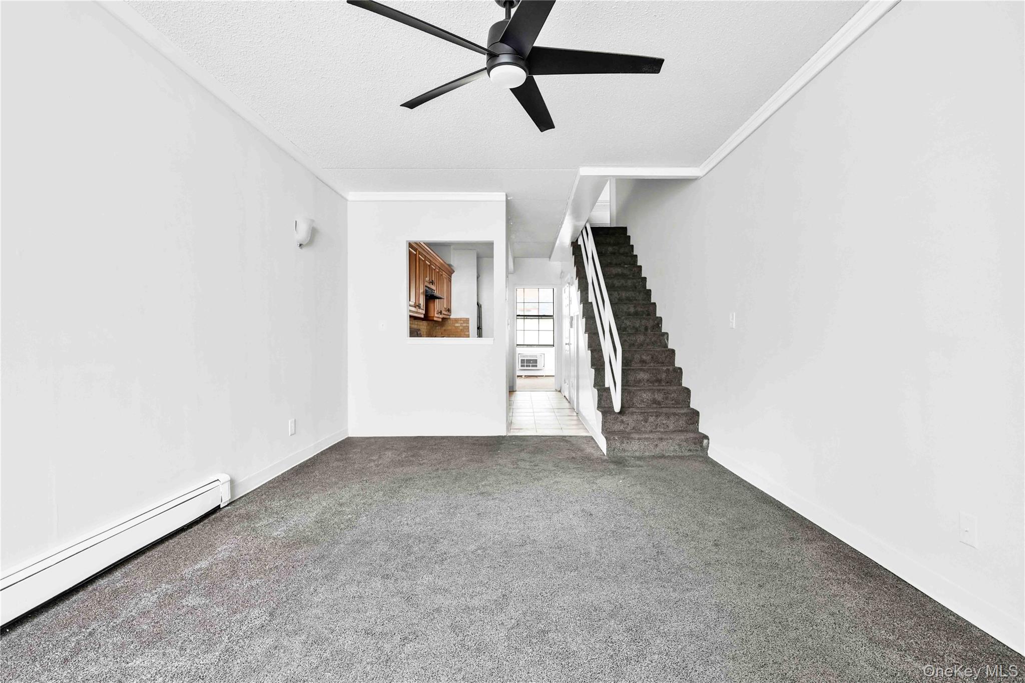 758 Brook Avenue, Unit 56C Bronx, NY 10455 - Photo 4 of 16 Unfurnished living room with stairway, baseboard heating, a ceiling fan, a textured ceiling, and carpet