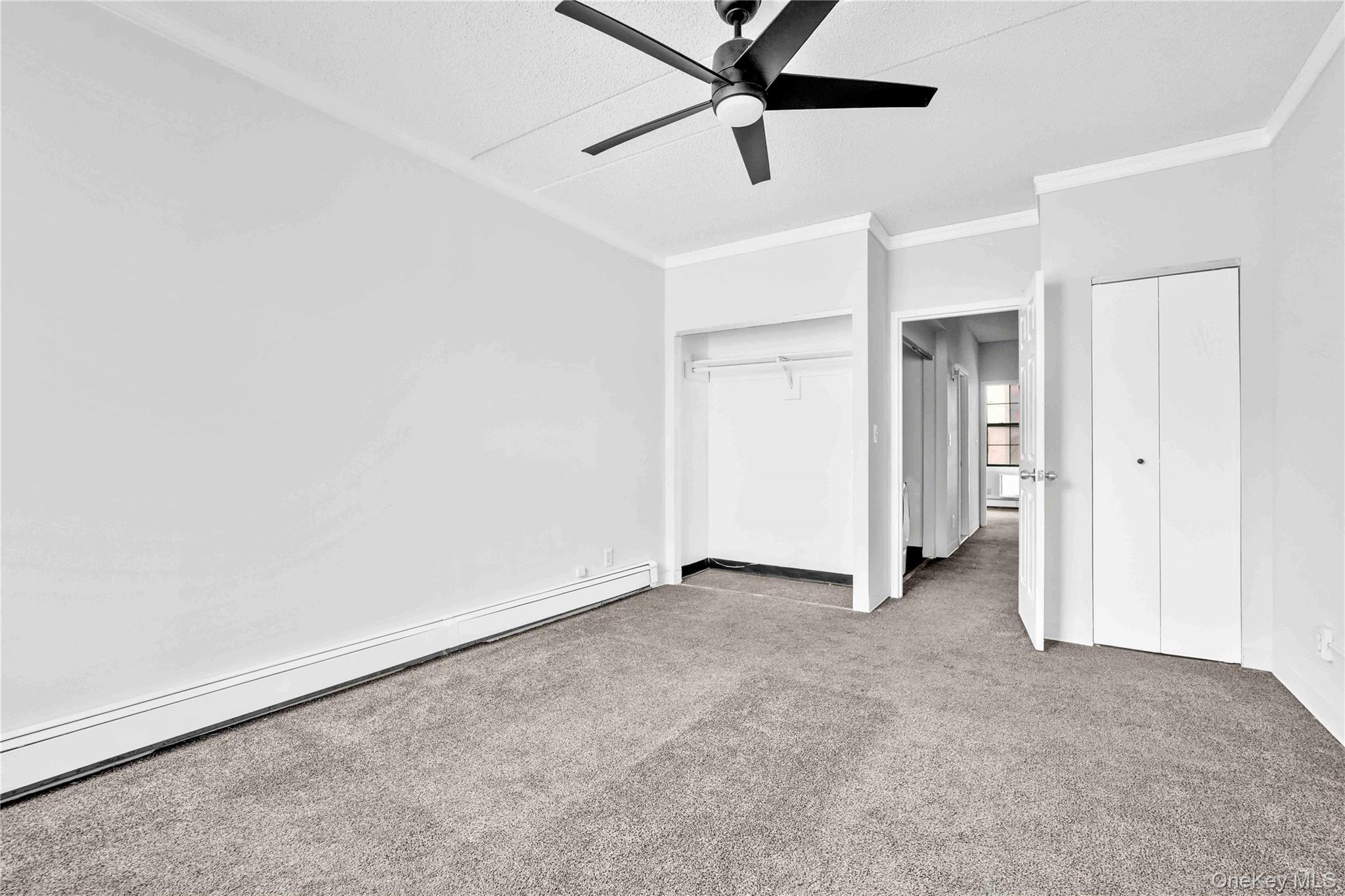 758 Brook Avenue, Unit 56C Bronx, NY 10455 - Photo 10 of 16 Unfurnished bedroom featuring a baseboard radiator, light colored carpet, crown molding, and ceiling fan