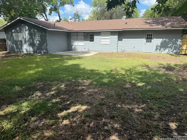 a view of a yard with a small house and a large tree