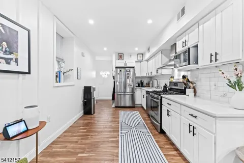 a kitchen with stainless steel appliances granite countertop lots of counter top space cabinets and wooden floor