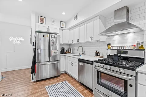 a kitchen with stainless steel appliances a refrigerator a stove and white cabinets