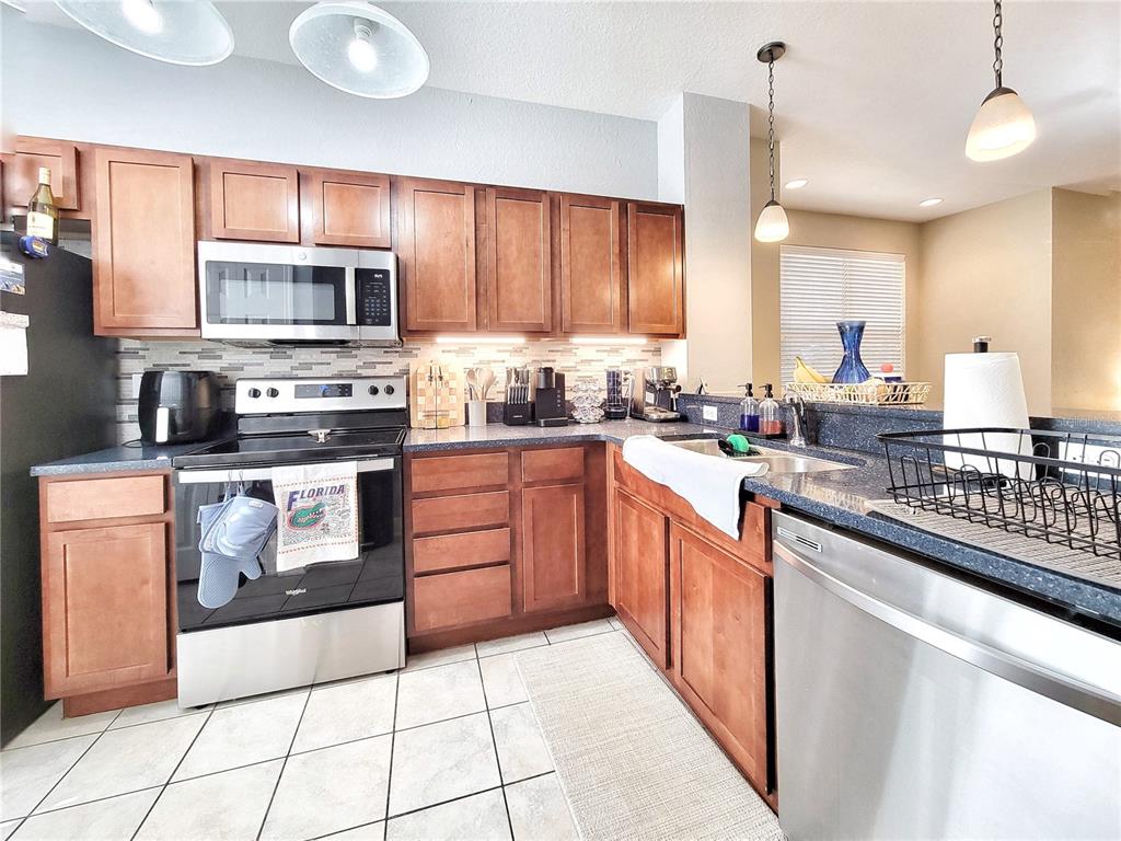 2508 Southwest 35th Place, Unit P91 Gainesville, FL 32608 - Photo 15 of 33 a large kitchen with stainless steel appliances granite countertop a stove top oven a sink dishwasher a dining table and chairs with wooden cabinets