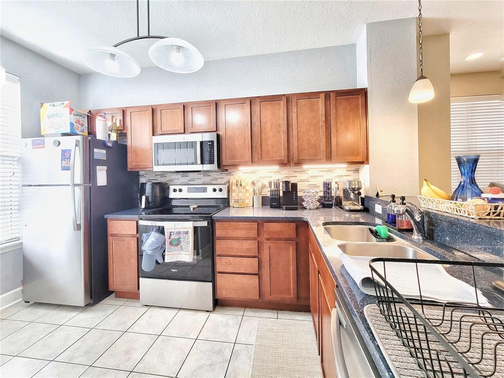 2508 Southwest 35th Place, Unit P91 Gainesville, FL 32608 - Photo 17 of 33 a kitchen with stainless steel appliances granite countertop a refrigerator oven a sink dishwasher and white cabinets with wooden floor