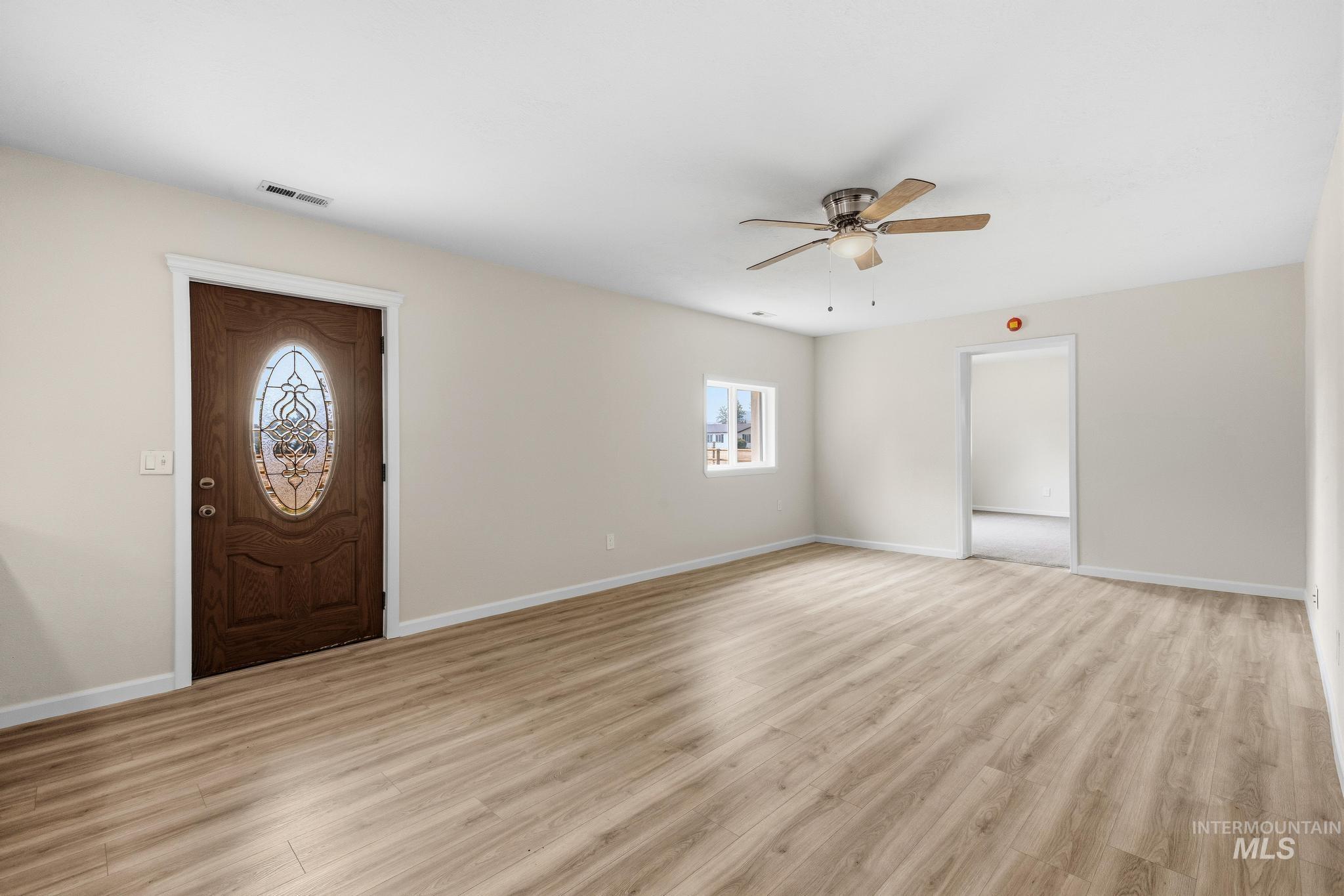 14666 Willis Road Caldwell, ID 83607 - Photo 12 of 50 Entryway featuring a decorative oval glass door, wood-finish flooring, a ceiling fan with light fixture, and neutral wall tones