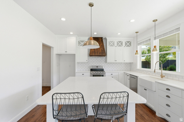 338 Windy Rdg Drive Smithfield, UT 84335 - Photo 13 of 63 Kitchen featuring a large center island with a white countertop, white shaker cabinetry, white subway tile backsplash, and a wood-finish range hood