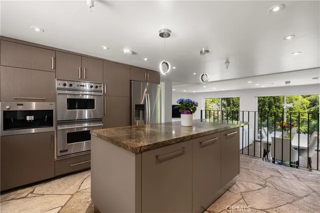 a kitchen with stainless steel appliances granite countertop a refrigerator a sink a stove and oven