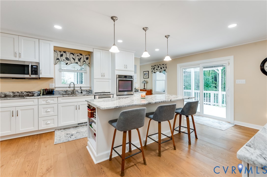 19229 Turkey Road Rockville, VA 23146 - Photo 21 of 44 a kitchen with stainless steel appliances granite countertop a stove a sink a microwave a dining table and chairs with wooden floor