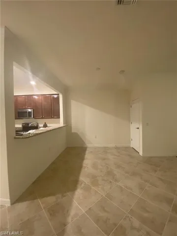 a view of kitchen and empty room with wooden floor