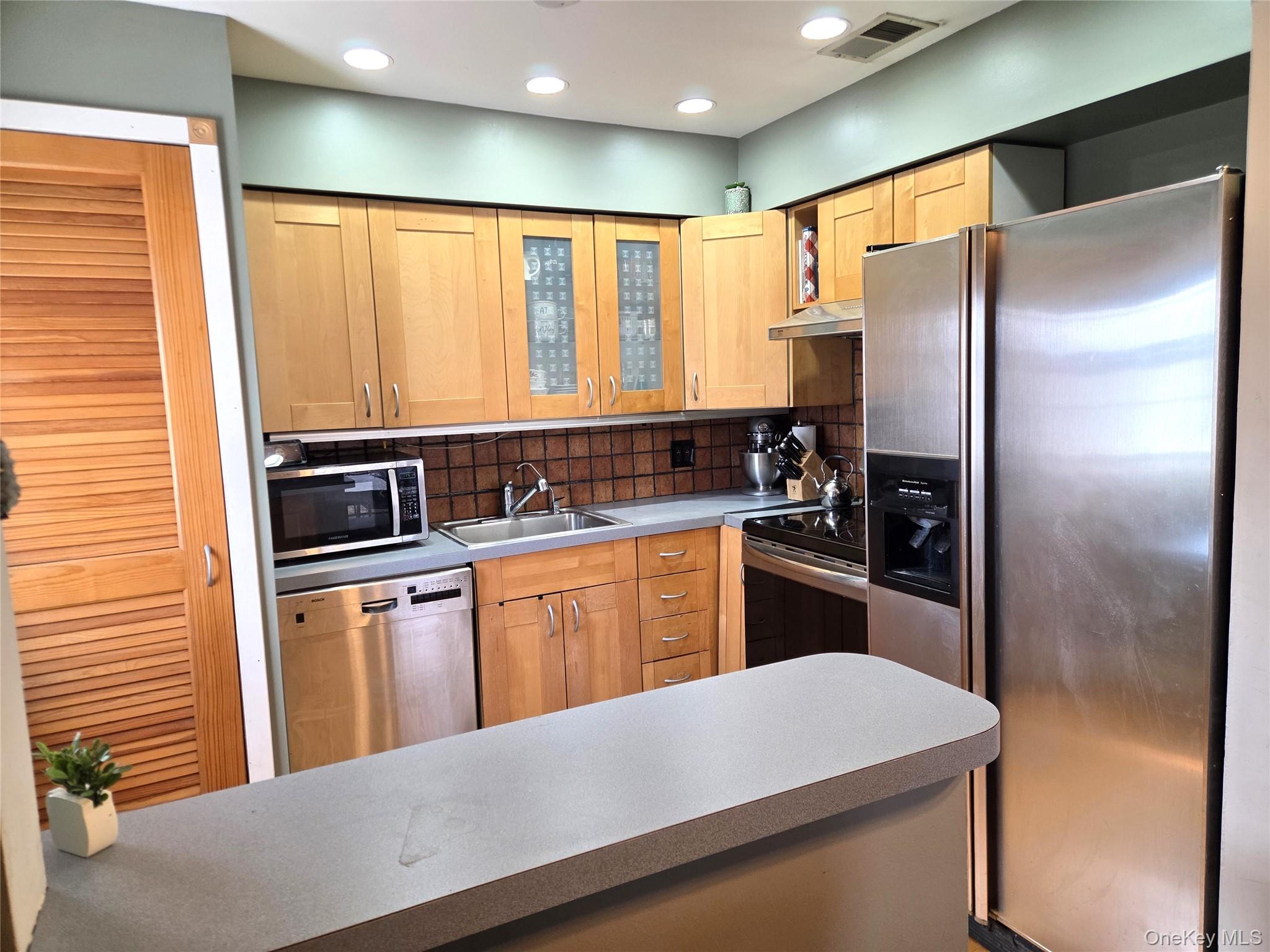 655 Middle Country Road, Unit 6A2 Coram, NY 11727 - Photo 12 of 19 The Updated Kitchen Offers Maple Cabinetry, Accent Glass Doors & Corner Cabinet, Tiled Backsplash, Hardwood Floors, Stainless Steel Appliances (Kitchen Aid Side By Side Refrigerator With Water & Ice Maker, Frigidaire Ceramic Top Stove, Range Hood, & Bosch Dishwasher) And A Door To Your Own Washer & Dryer!