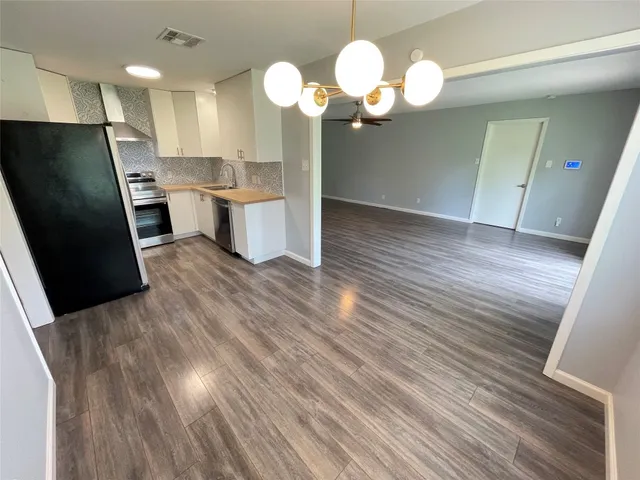 a view of a kitchen with wooden floor and stainless steel appliances