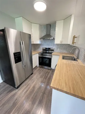 a kitchen with granite countertop a refrigerator and a stove top oven