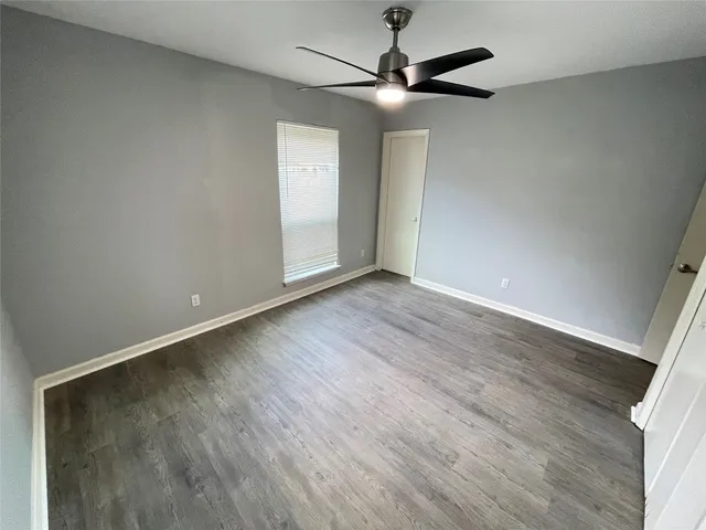 an empty room with wooden floor fan and windows