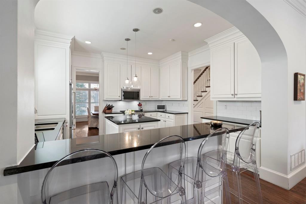 6936 Pasadena Avenue Dallas, TX 75214 - Photo 14 of 39 a kitchen with stainless steel appliances kitchen island granite countertop a stove a sink a refrigerator and white cabinets