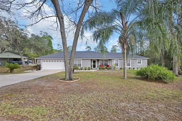 a view of a house with a yard and large trees