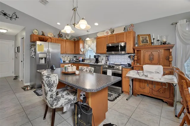 a kitchen with stainless steel appliances granite countertop a stove top oven a sink a dining table and chairs