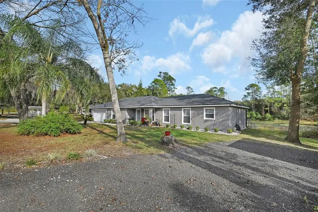 a view of a house with a big yard and large trees