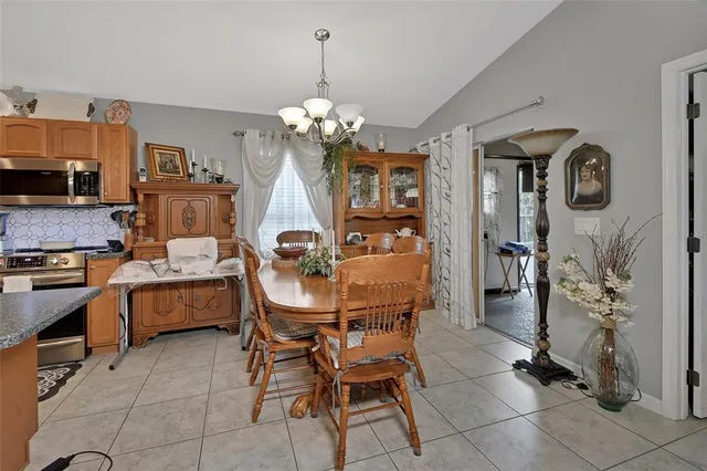 a dining room filled a chandelier and kitchen view