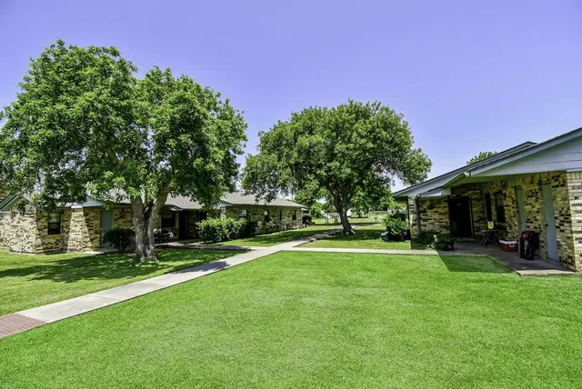 a view of a house with a big yard and a large trees