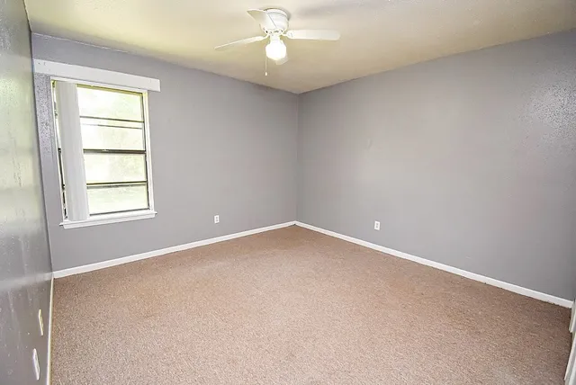 an empty room with a window and a fan