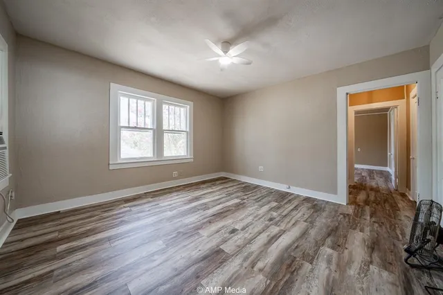 a view of an empty room with wooden floor and a window