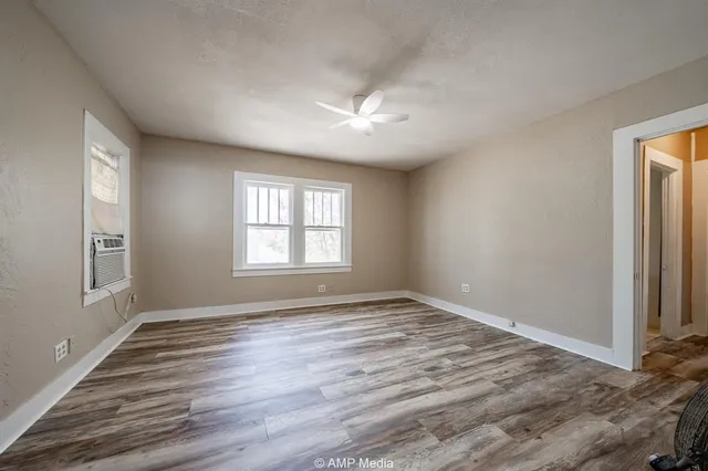 a view of an empty room with wooden floor and a window