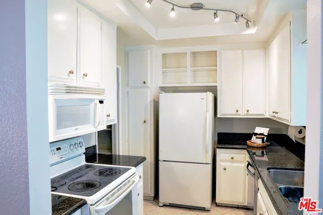 a kitchen with granite countertop a refrigerator stove and sink