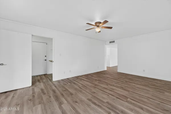 a view of empty room with wooden floor and ceiling fan