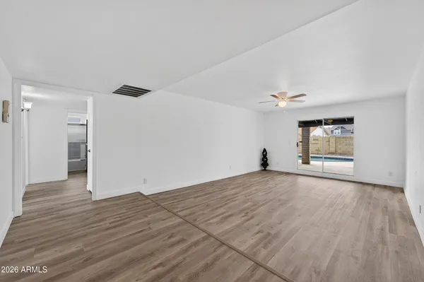 an empty room with wooden floor cabinet and windows