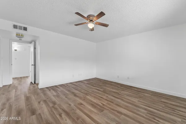 an empty room with wooden floor and ceiling fan