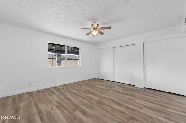 a view of empty room with wooden floor and ceiling fan