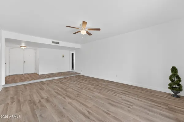 a view of empty room with wooden floor and ceiling fan