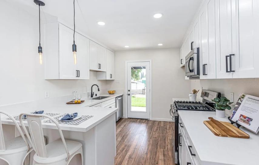 635 Paraiso Avenue Spring Valley, CA 91977 - Photo 21 of 27 a kitchen with stainless steel appliances granite countertop a stove top oven a sink a dining table and chairs with wooden floor